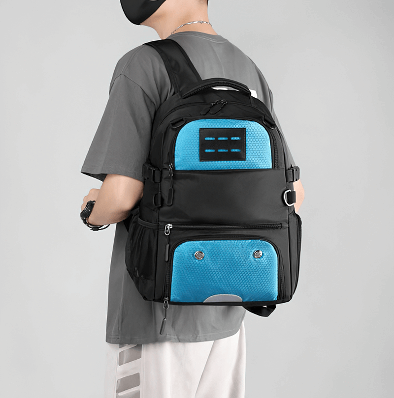 Black sports backpack with blue accents, featuring shoe compartment and detachable net pocket, worn by a person on their back.